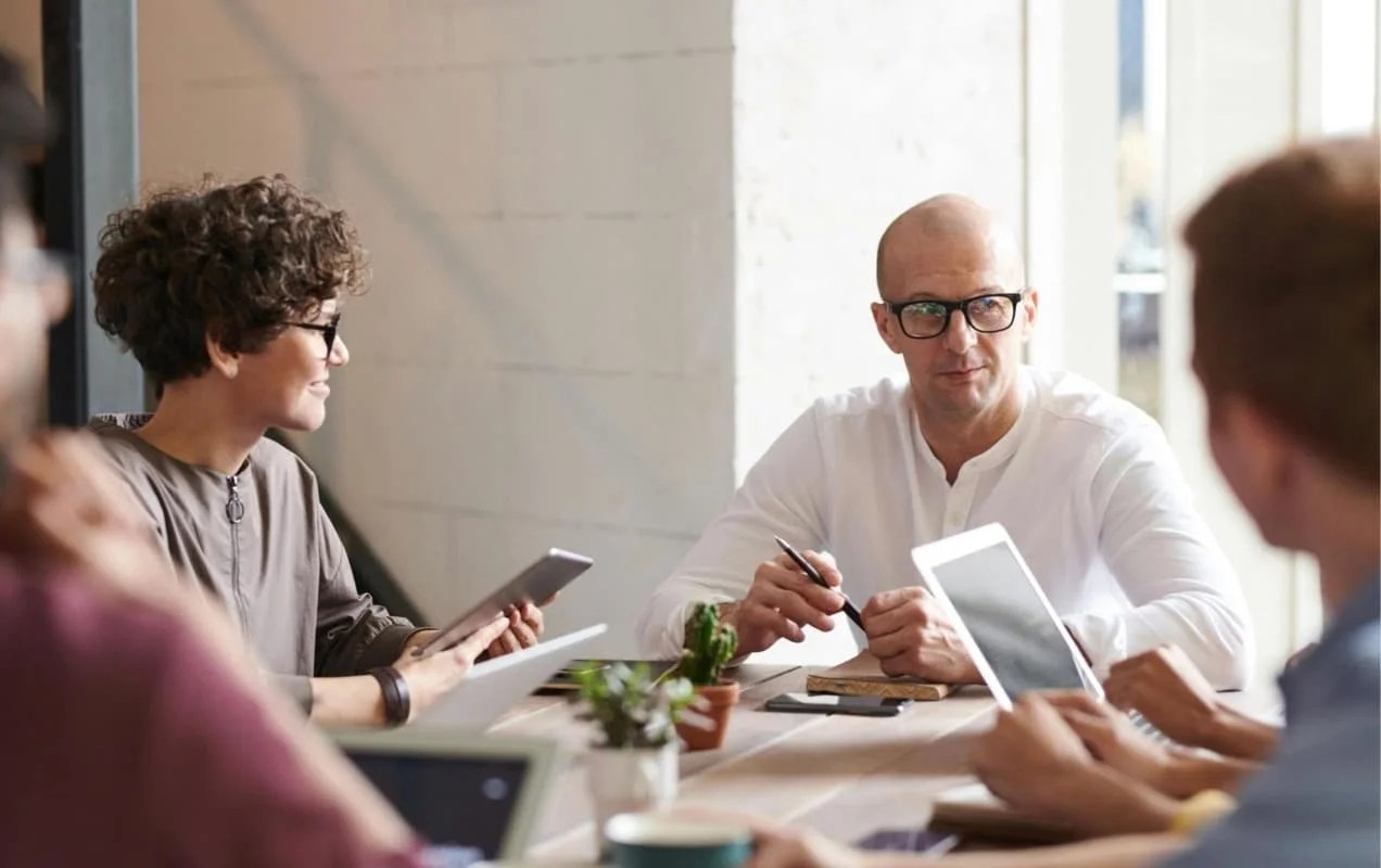 team members discussing something at a table, all with tablets